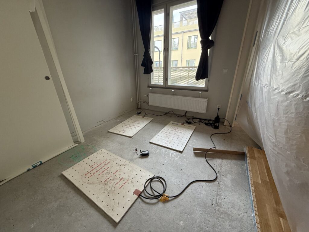 Översiktsbild av sovrum efter rivning av fuktskadad parkett. Golvkonstruktionen har frilagts för uttorkning och kontrollmätning av betongplattan. Fuktsonder och distansavläsningsutrustning har installerats för löpande uppföljning av uttorkningsförloppet.